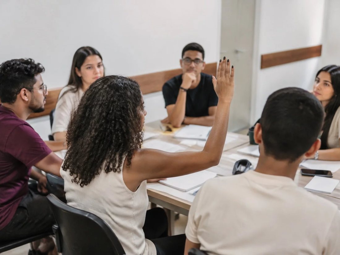 Participantes conversando de pé no corredor entre estantes de uma biblioteca